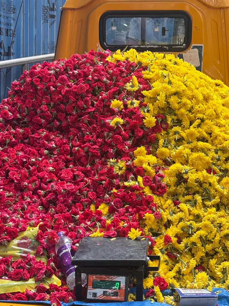 A flower cart overflowing with red roses and golden marigolds